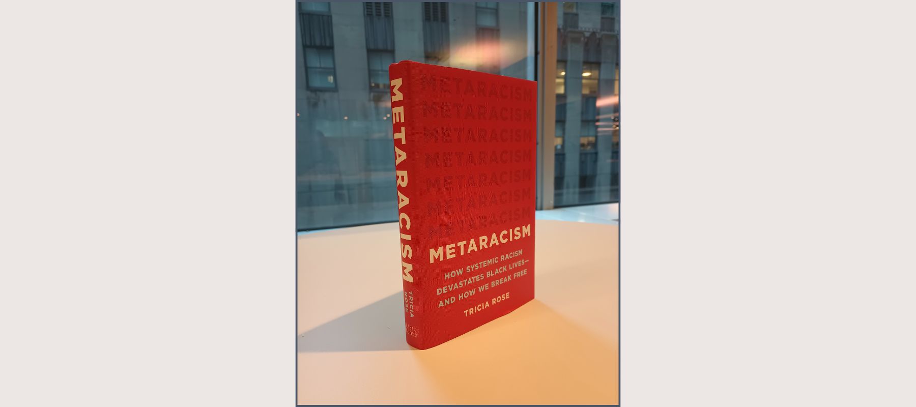 red covered book entitled metaracism standing on a shelf in front of a window