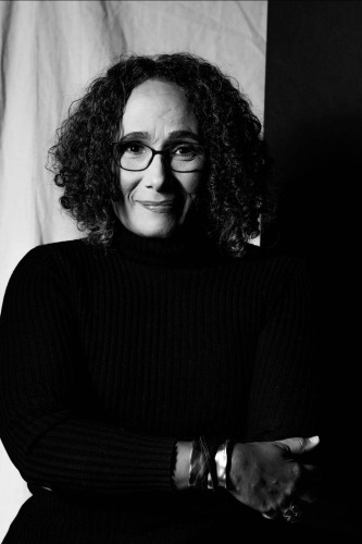 A woman standing with folded arms, confidently looking at the camera