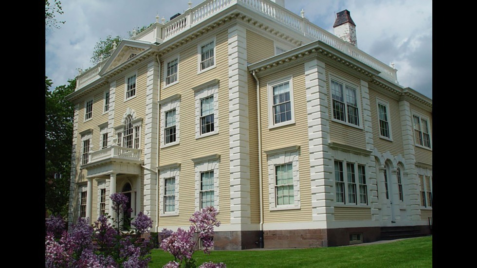 exterior angled view of a large yellow victorian manor