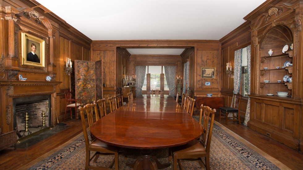 interior long view of a wood paneled room with a long wooden dining table in the center